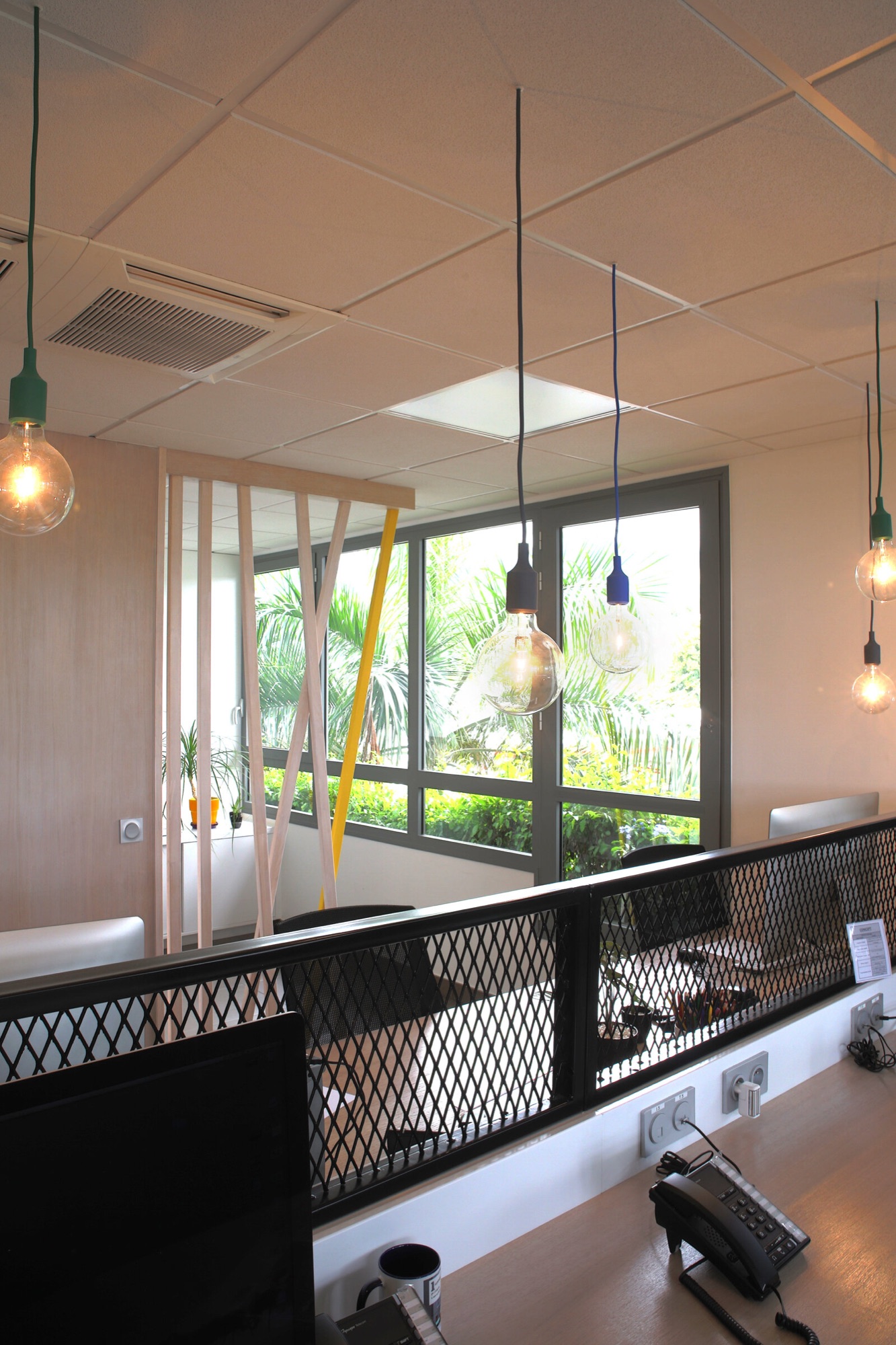 Agence de communication, bureaux — open space : suspensions à câbles colorés, garde-corps en métal déployé noir et grande baie vitrée
