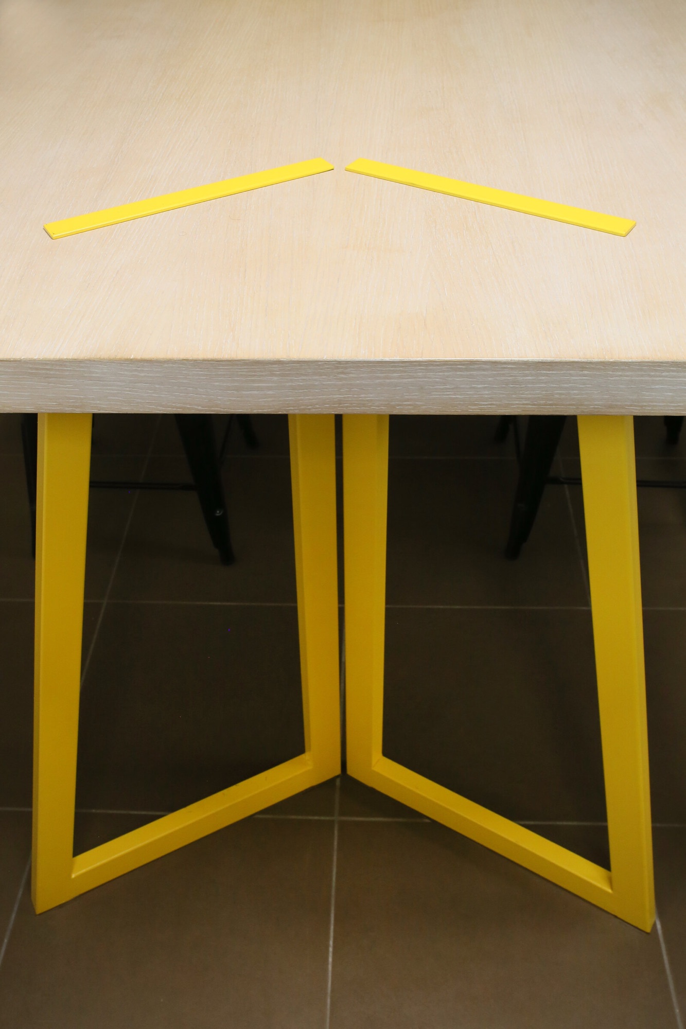 Agence de communication, bureaux — détail des pieds de table jaunes et des filets jaunes incrustés dans le plateau