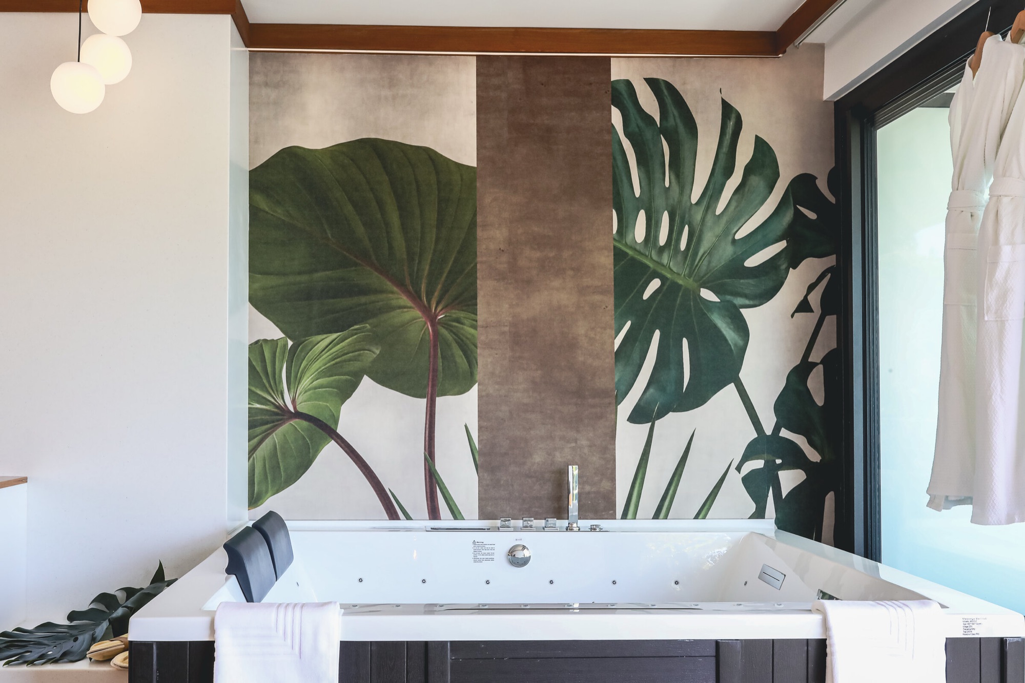 Hôtel Le Tahiti, Arue — suite : baignoire spa face à un panneau mural de grandes feuilles tropicales