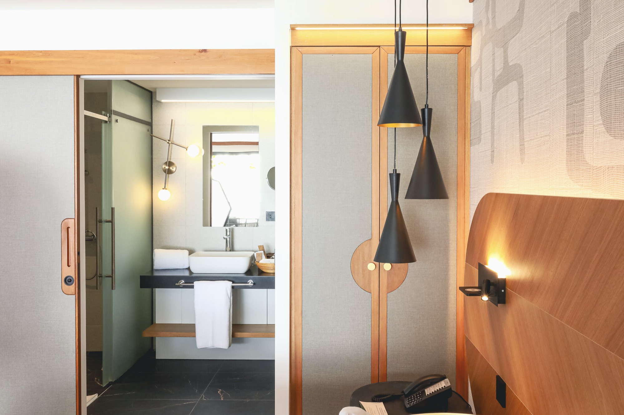 Hôtel Le Tahiti, Arue — suite : porte coulissante sur la salle de bain, armoire habillée de tissu et suspensions noires