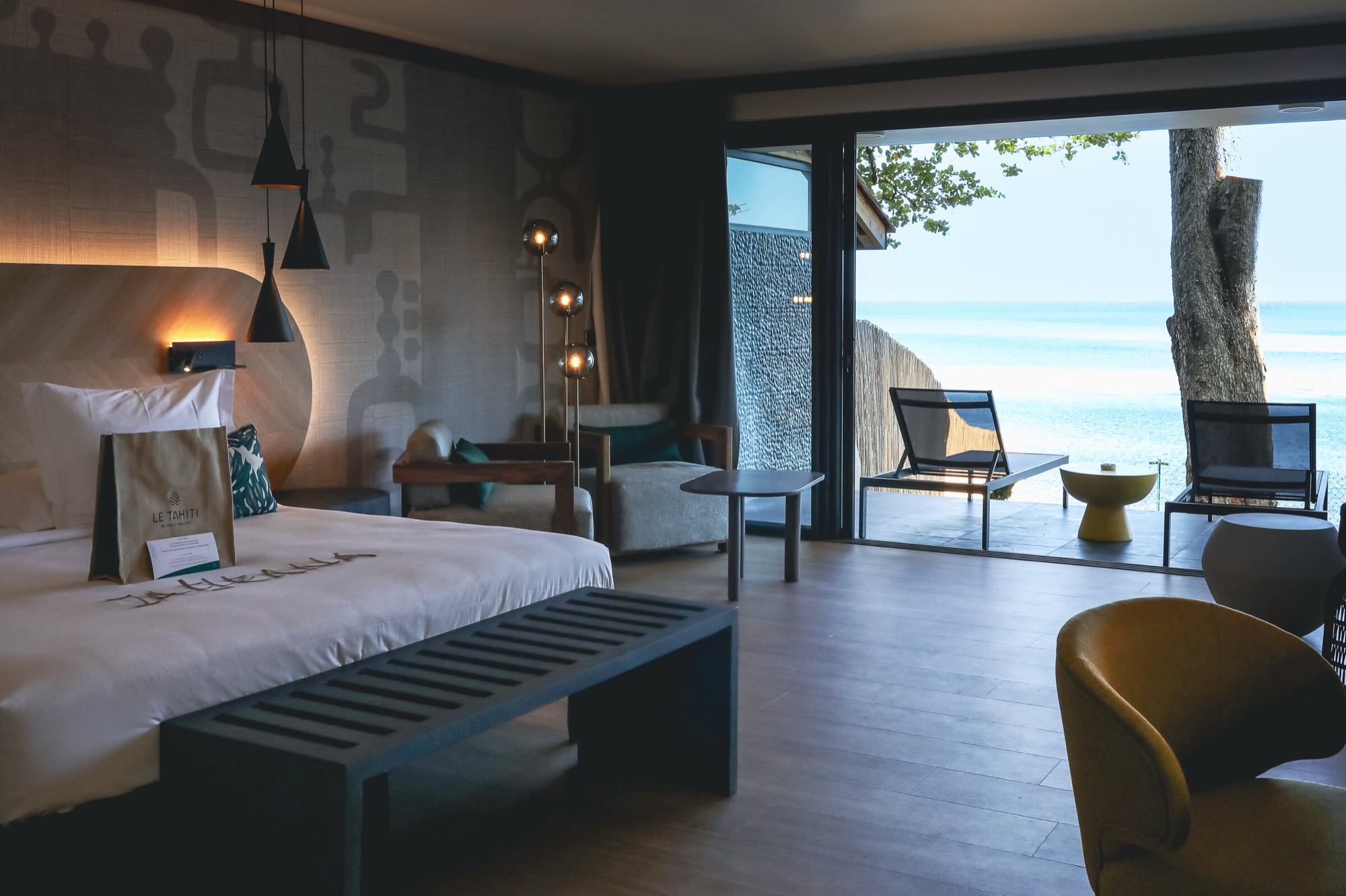 Hôtel Le Tahiti, Arue — suite : chambre ouverte sur la terrasse et l'océan, banc en pierre au pied du lit