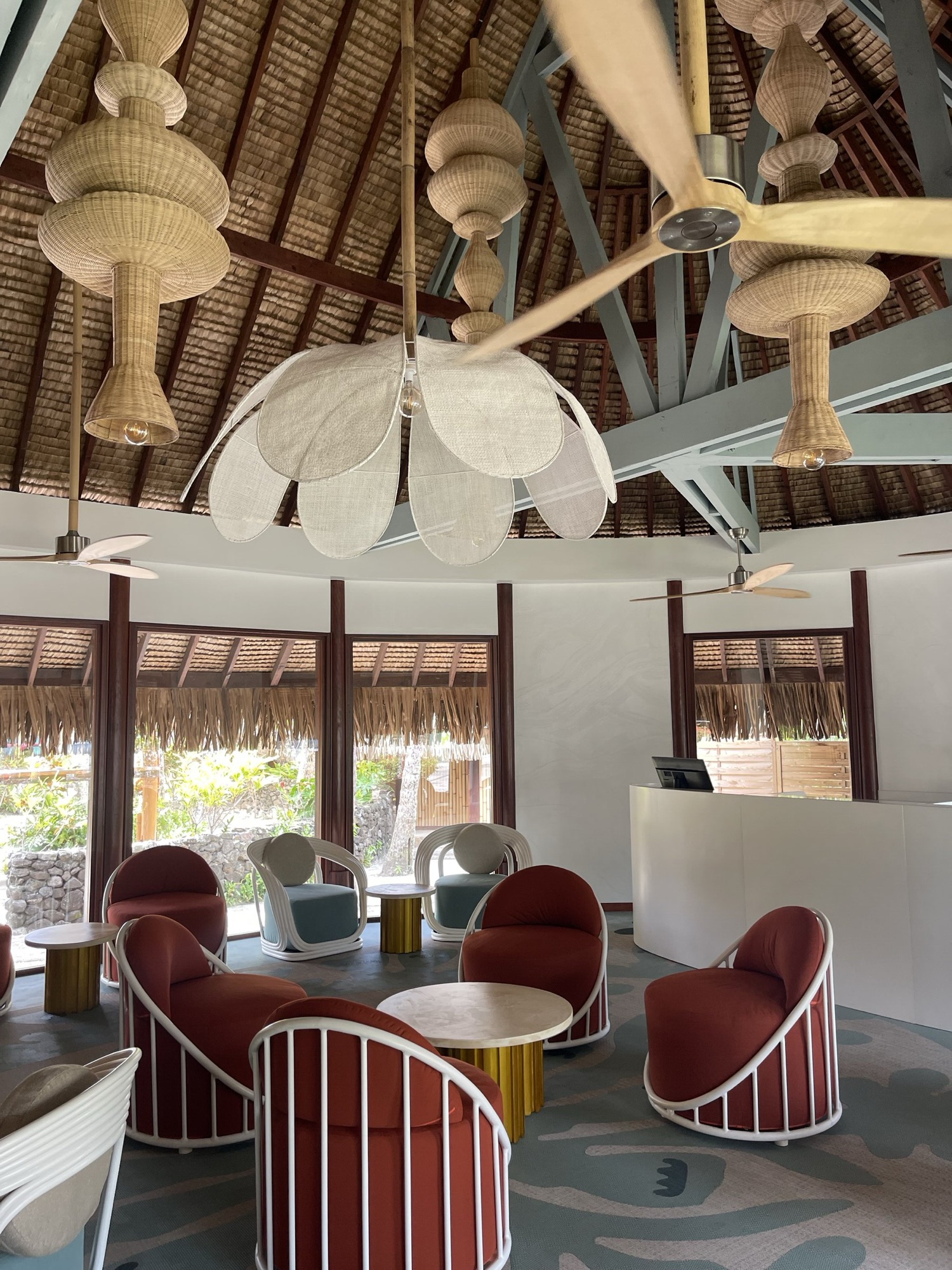 InterContinental Bora Bora, lobby — salon lounge : fauteuils terracotta et rotin blanc sous les suspensions en fleurs
