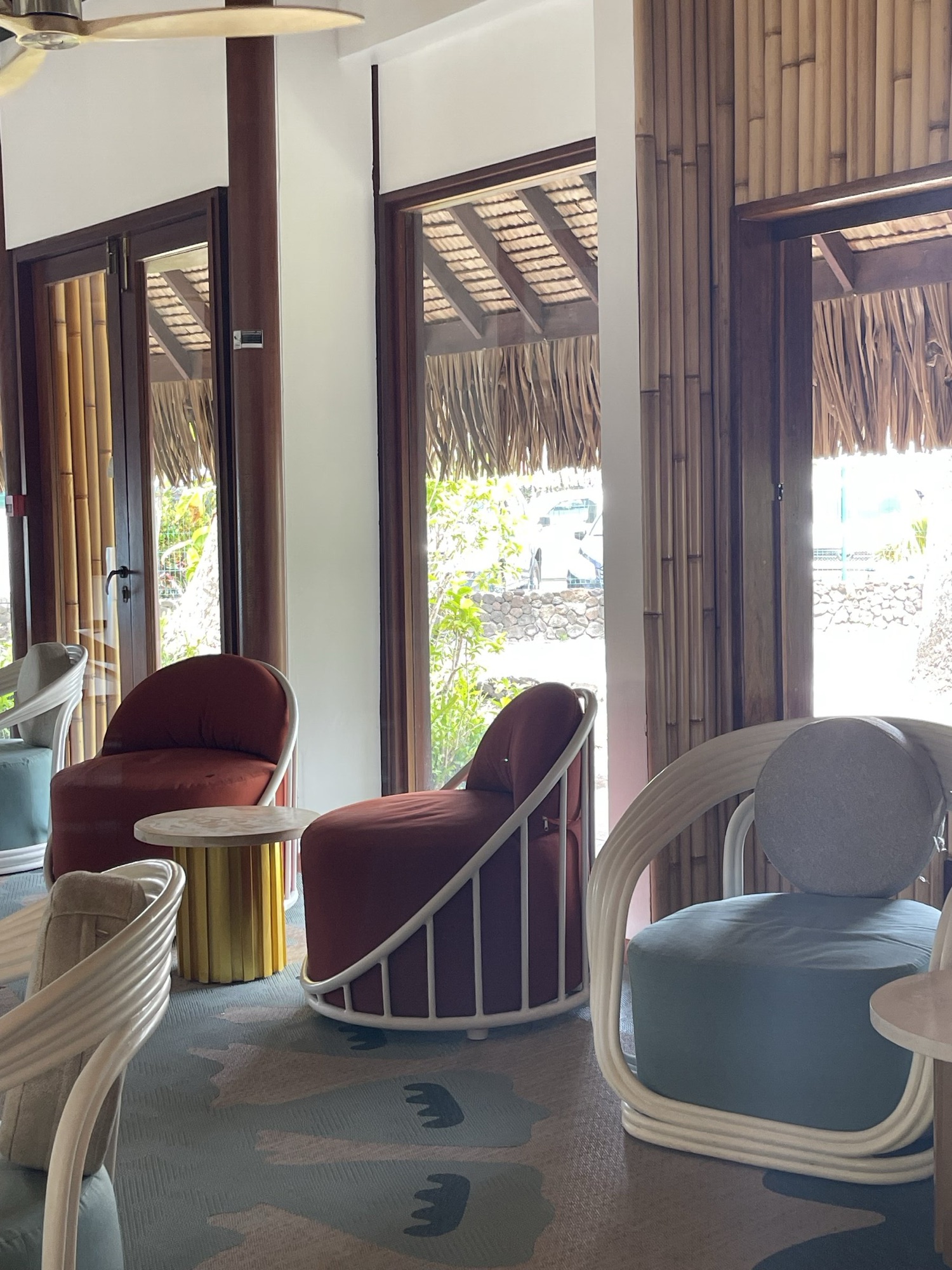 InterContinental Bora Bora, lobby — fauteuils terracotta et rotin devant les portes-fenêtres en bois et bambou