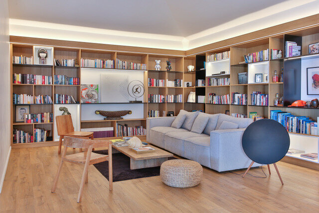 Maison particulière — salon bibliothèque sur mesure en bois, canapé gris et enceinte bleue